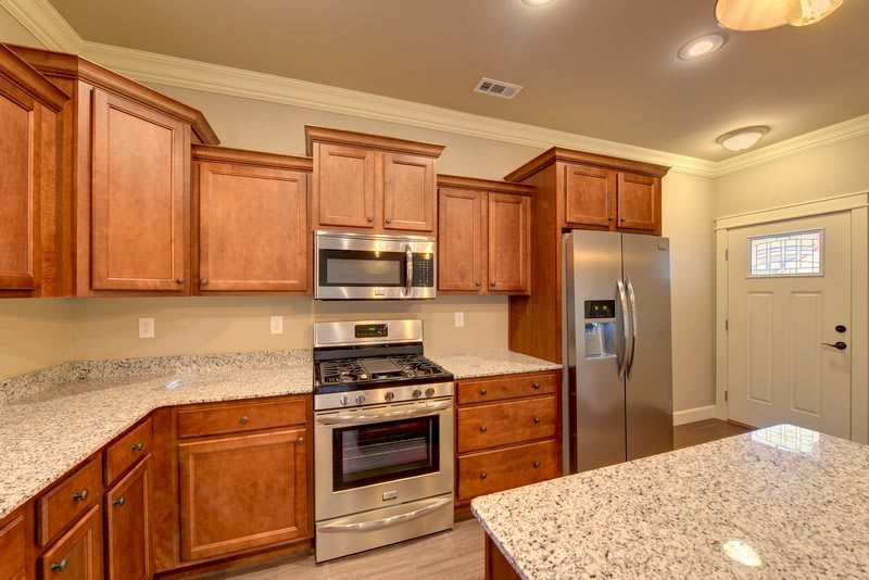 A modern kitchen with wooden cabinets, stainless steel appliances, and a granite countertop.
