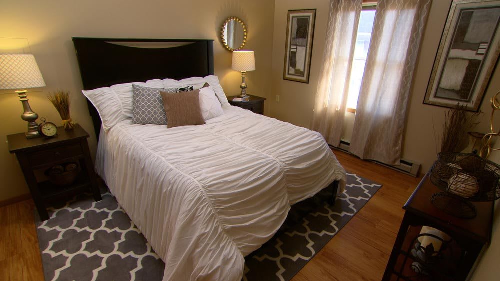 A cozy bedroom with a neatly made bed, stylish decor, and natural lighting.
