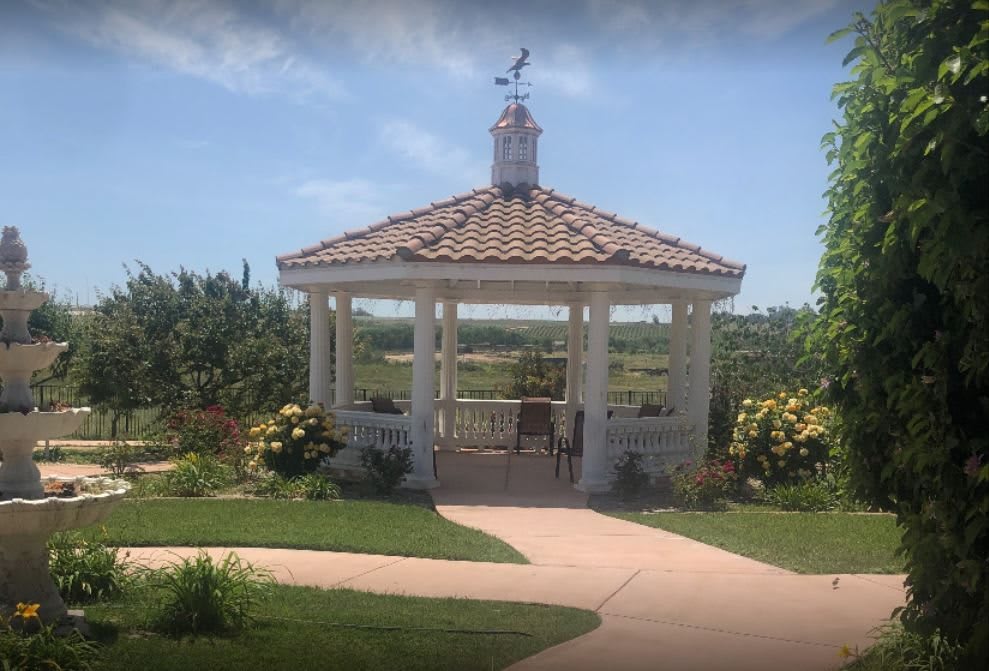 A charming gazebo set in a lush garden with clear blue skies.