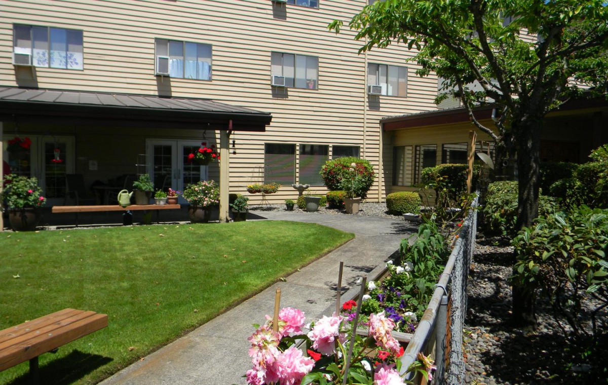 A serene garden with colorful flowers and a well-maintained pathway beside a residential building.