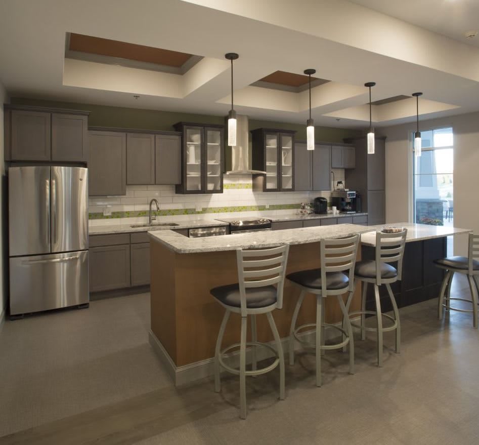 A modern kitchen with a central island, featuring pendant lighting and stainless steel appliances.