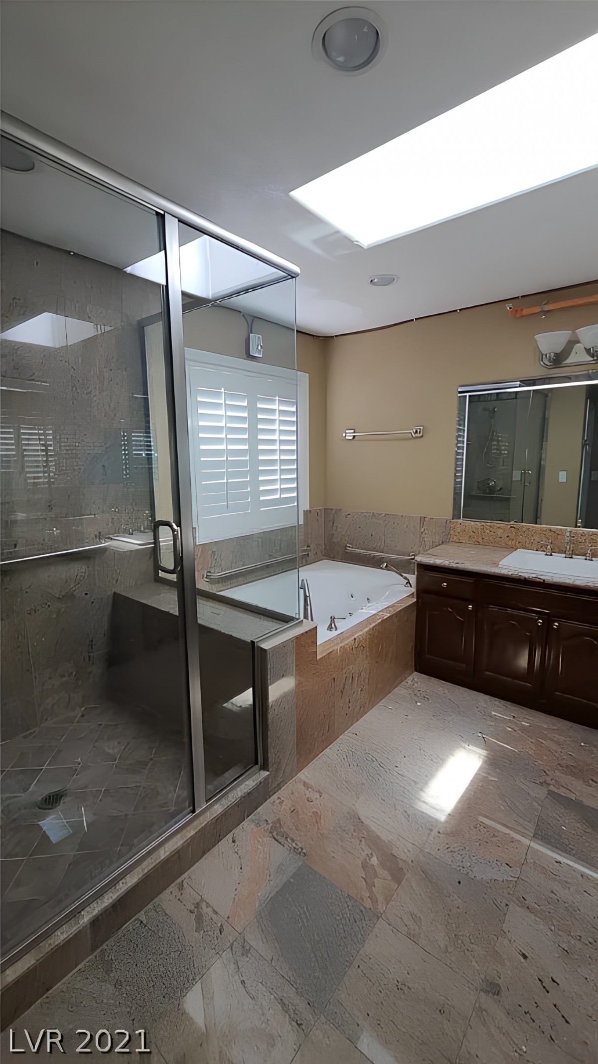 A modern bathroom featuring a glass-enclosed shower, a separate bathtub, and a large mirror above a wooden cabinet.