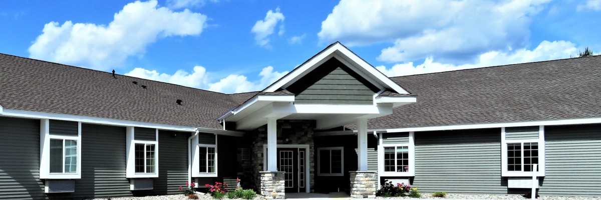 A modern house with a gabled roof and stone accents under a blue sky.
