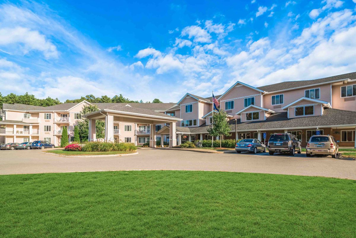 A spacious residential building with a landscaped lawn and a driveway under a blue sky.