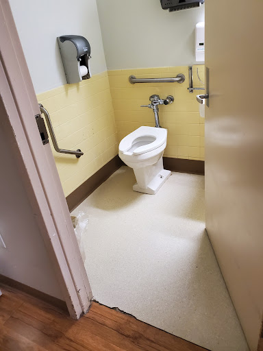 A view of an accessible bathroom featuring a toilet and safety handrails.