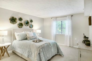 A bright and minimalist bedroom with soft decor, featuring a neatly made bed and wall art.