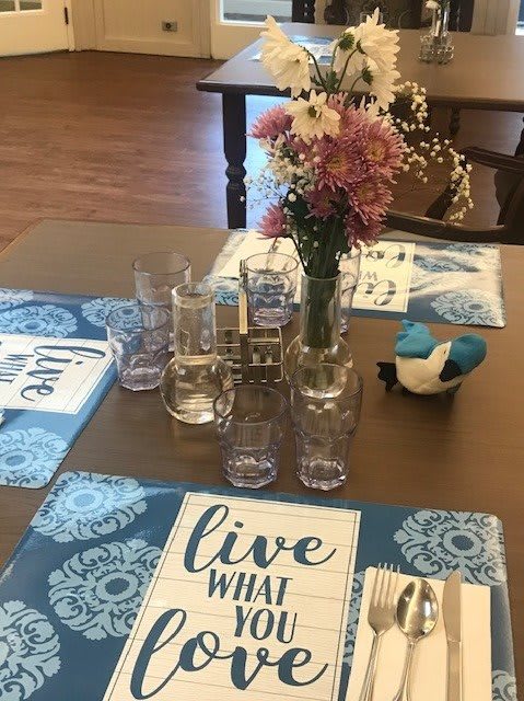 A beautifully set dining table with floral arrangements and inspirational placemats.