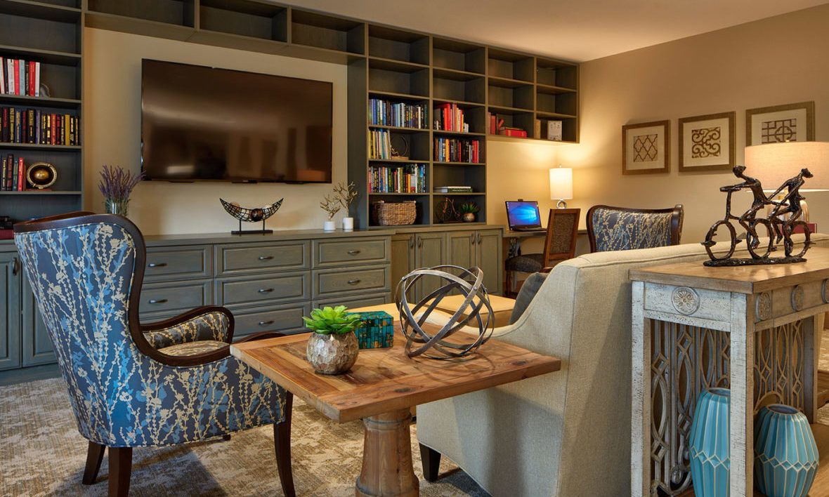 A cozy living room featuring modern furniture, bookshelves, and a large television.