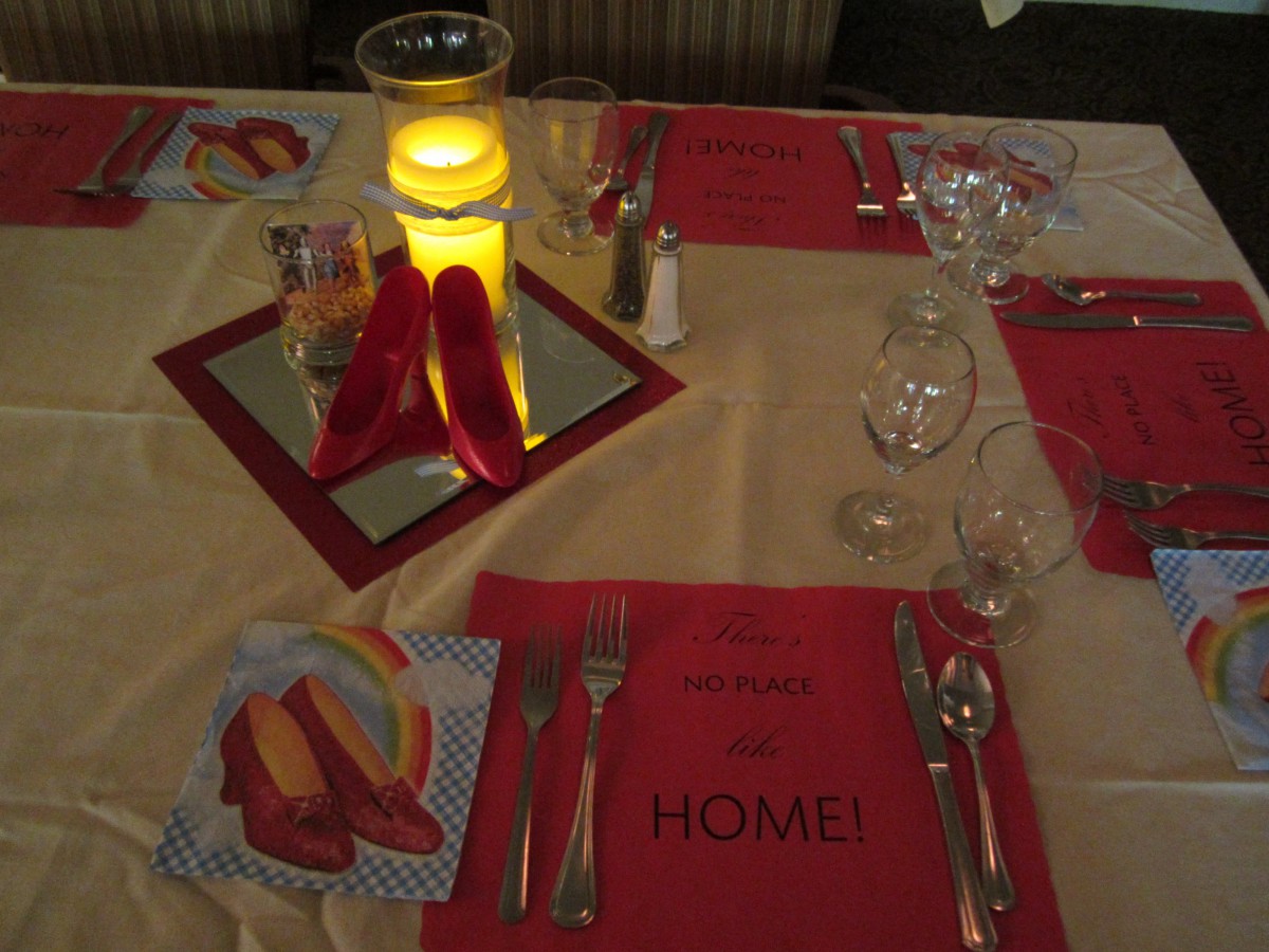A beautifully set dinner table with red placemats, a glowing candle centerpiece, and neatly arranged cutlery and glassware.