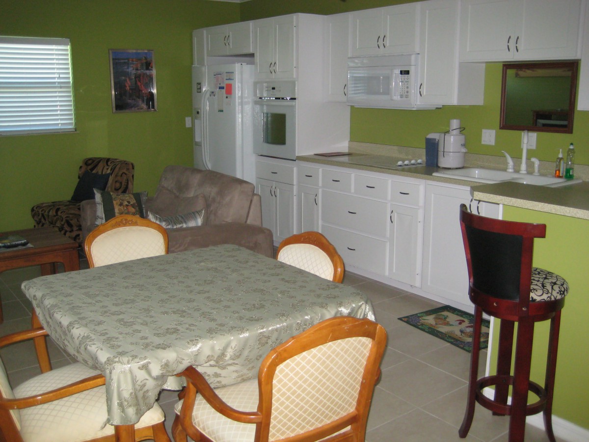 A cozy kitchen and dining area with white cabinets against green walls.