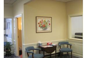 A small waiting area with two chairs, a table, and a painting on the wall.