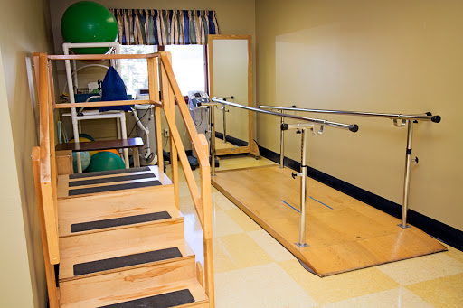A well-equipped physical therapy room featuring stairs and parallel bars for rehabilitation exercises.