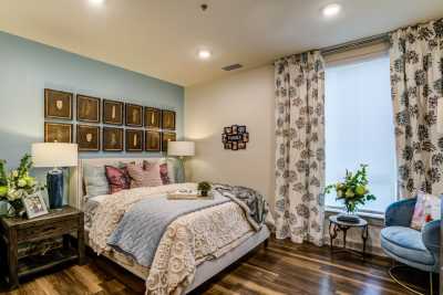 A cozy bedroom with elegant decor, featuring a comfortable bed, decorative pillows, floral curtains, and wall art.