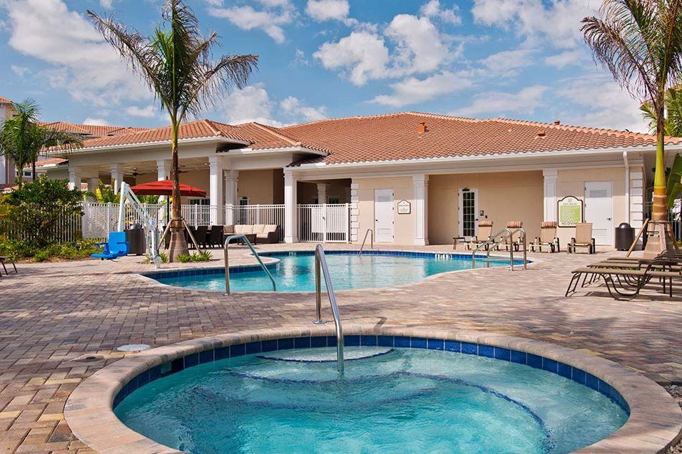 A relaxing resort with a swimming pool and tropical palm tree under a sunny sky.