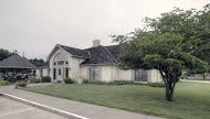 A suburban house with a lawn and trees in front.