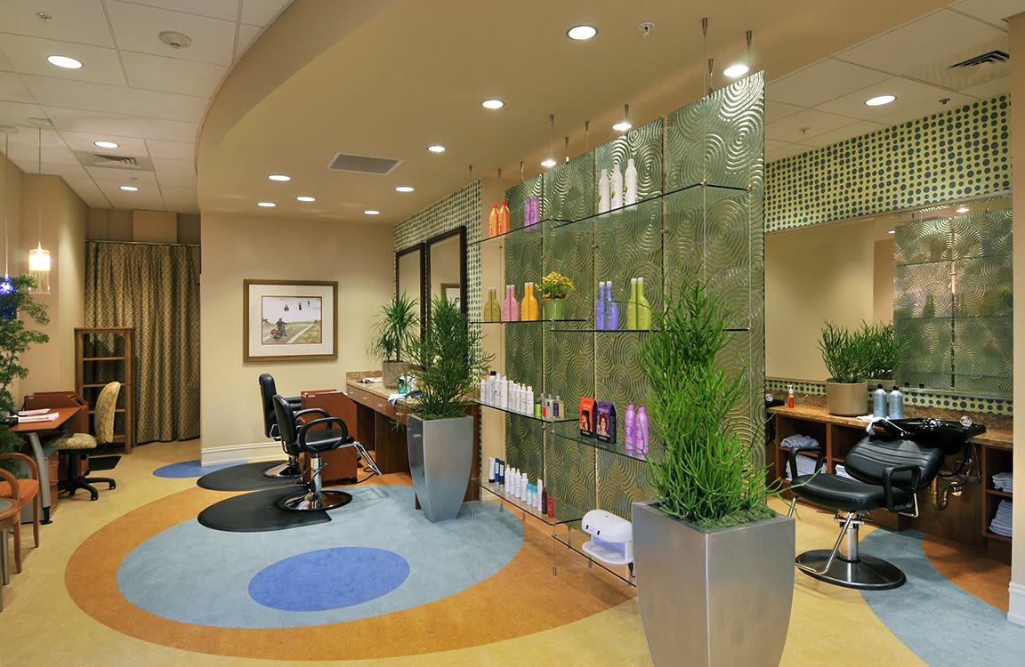 A modern salon interior featuring stylish furniture, beauty products on display shelves, and decorative plants.