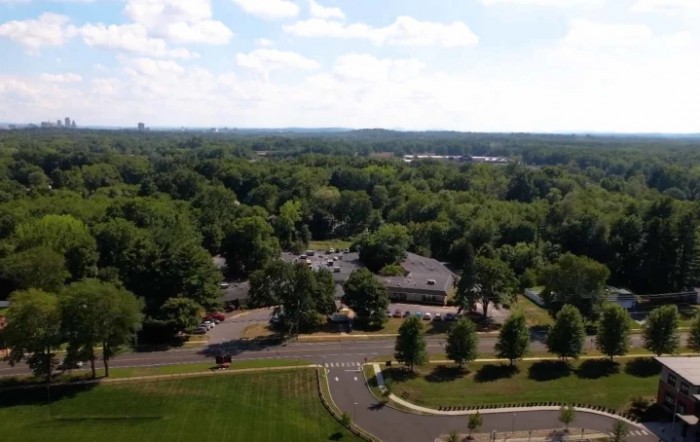 Aerial view of a landscape with lush greenery, buildings, and roads.