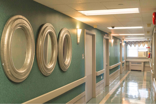 A well-lit hallway featuring decorative mirrors and green walls.