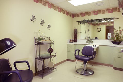 A cozy hair salon interior with a styling chair, mirror, and decorative elements.