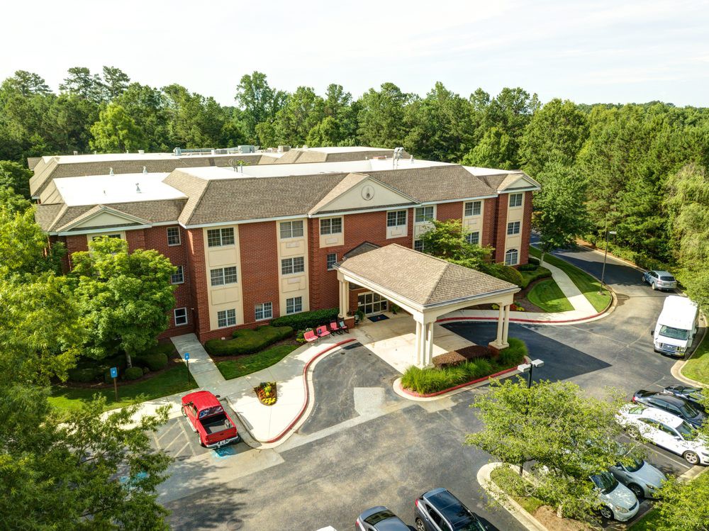Aerial view of a residential building surrounded by trees and a parking lot.