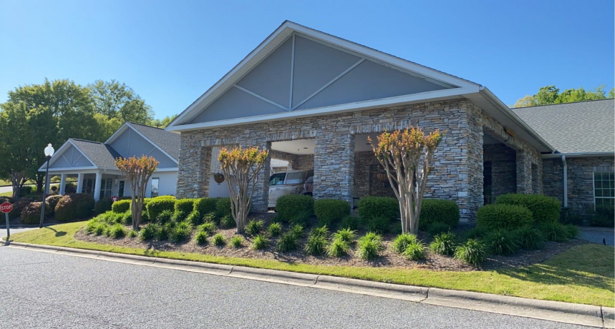 A modern building with a brick facade and well-maintained landscaping on a sunny day.