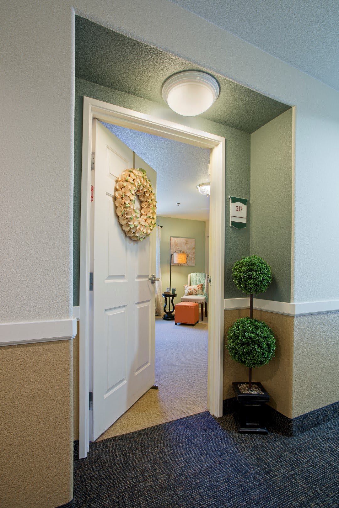 A welcoming doorway with a wreath and potted plants leading into a cozy room.