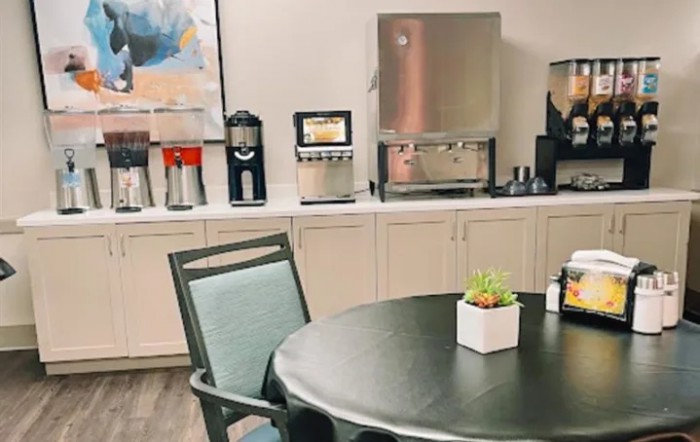 An office break room featuring a coffee station and a table with chairs.
