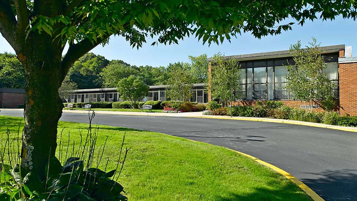 A modern office building surrounded by lush greenery and a well-maintained lawn.