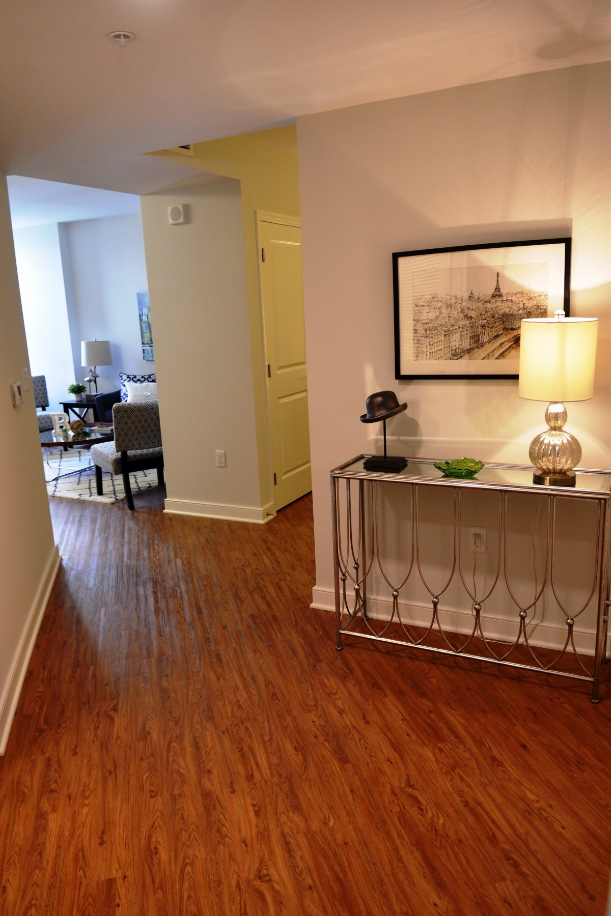 A stylish hallway featuring a console table with decorative items, a lamp, and framed artwork on the wall.