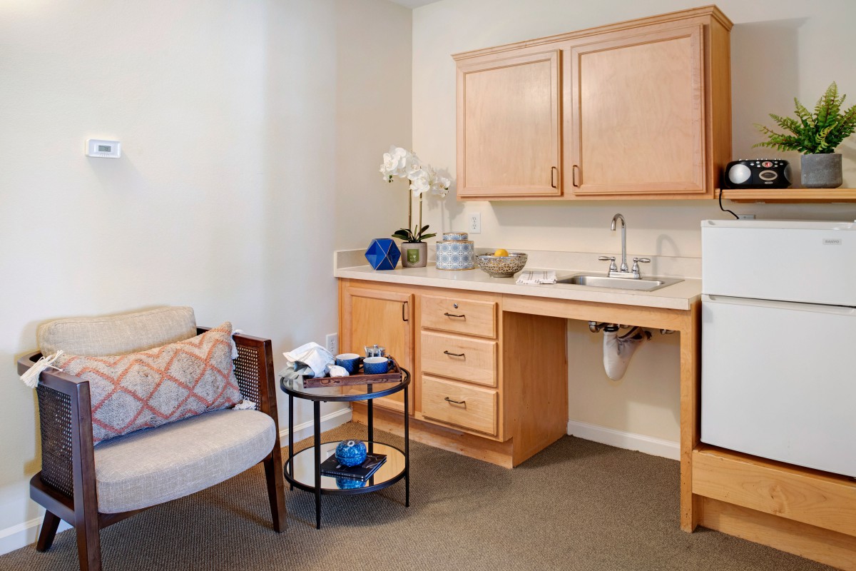 A cozy kitchenette area with light wood cabinets, a small round table, and comfortable seating.