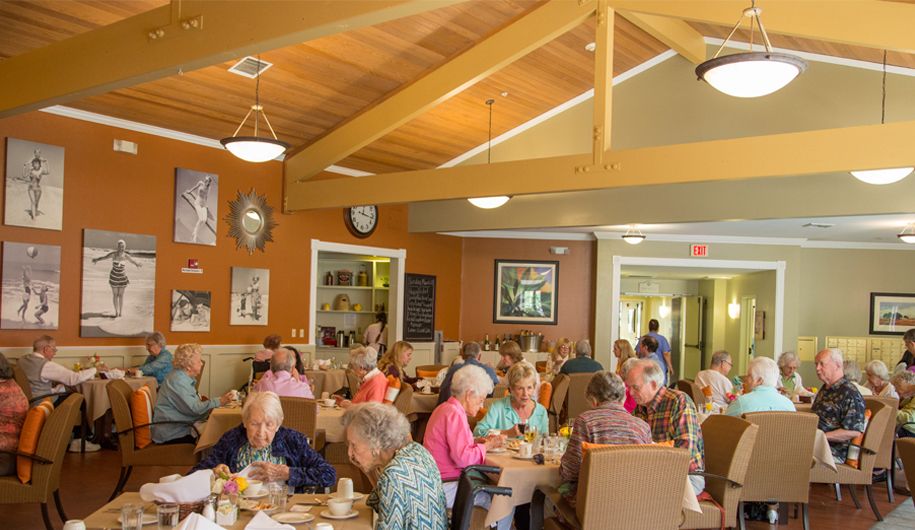 A lively dining hall with seniors enjoying a meal together.