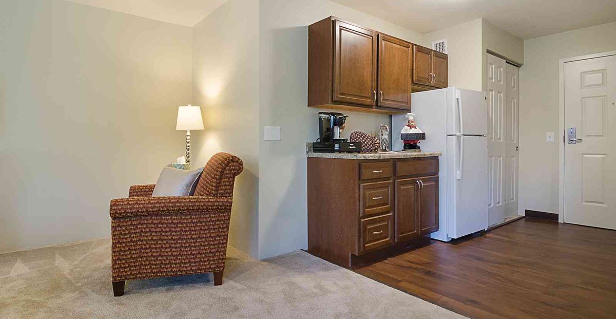 A cozy living space with a compact kitchen area featuring wooden cabinets and a refrigerator.