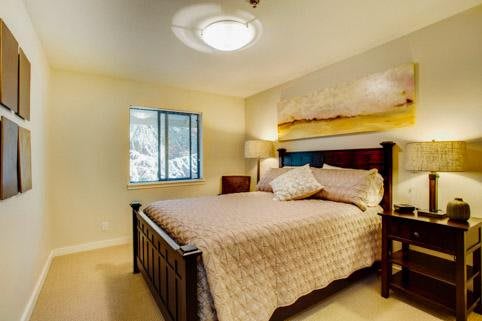 A cozy bedroom with a large bed, bedside lamp, and window.