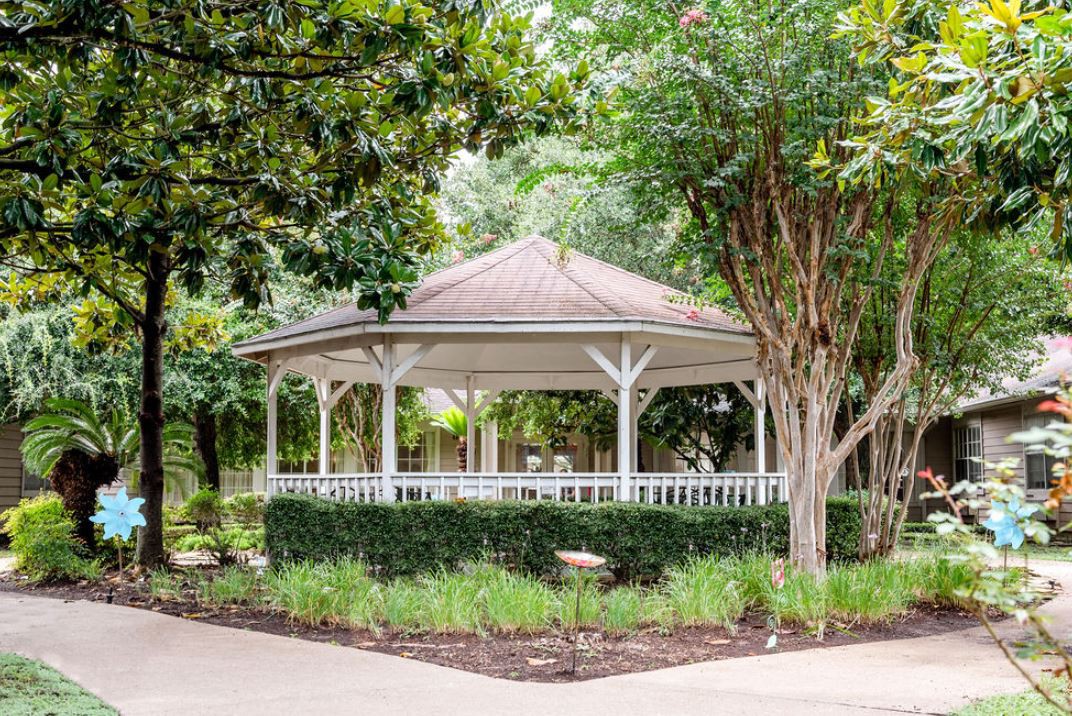 A charming gazebo surrounded by lush greenery in a peaceful park setting.