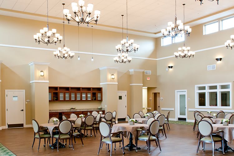 A spacious dining area with elegant chandeliers and neatly arranged tables and chairs.