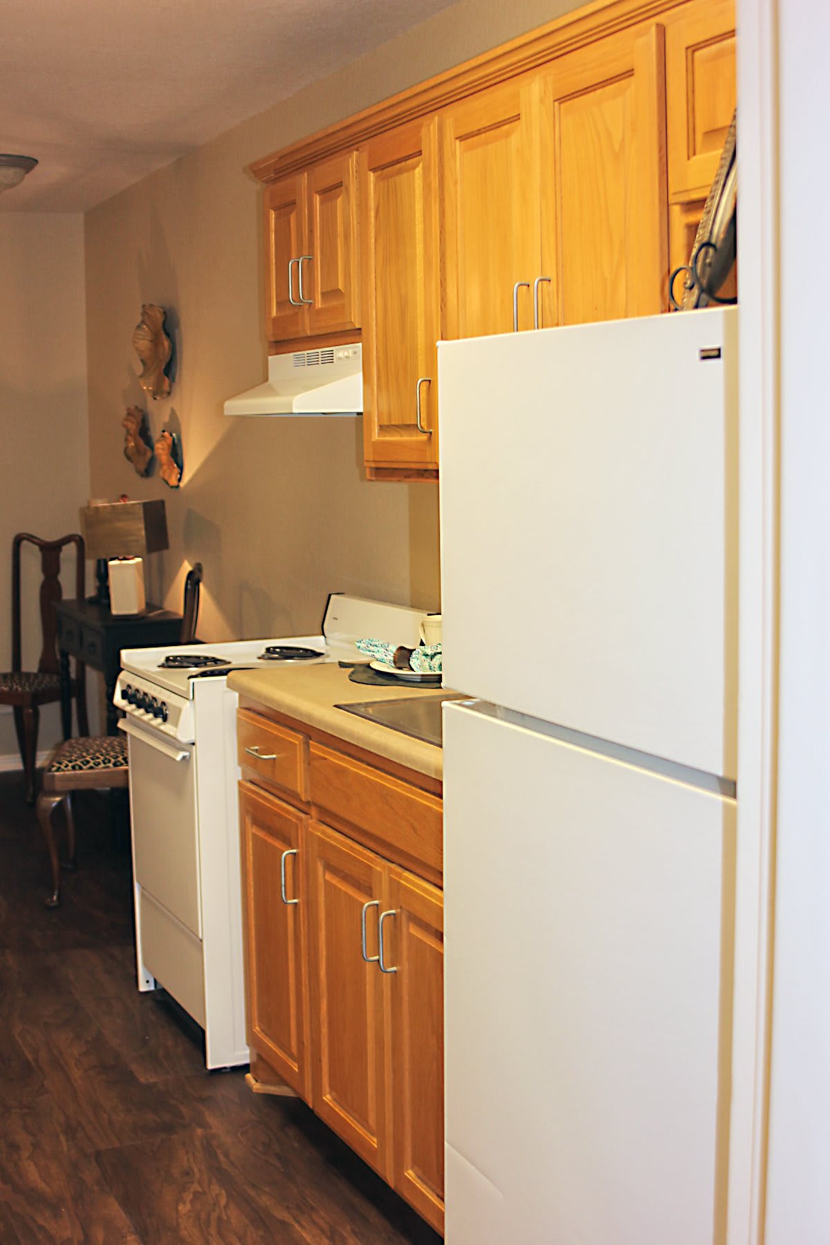 A compact kitchen with wooden cabinets, a refrigerator, and a stove.