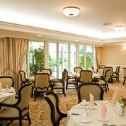 An elegant dining room with neatly arranged tables and chairs, featuring large windows and decorative curtains.