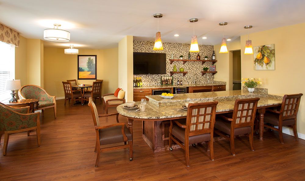 A modern kitchen and dining area featuring a granite countertop, wooden chairs, and elegant pendant lighting.