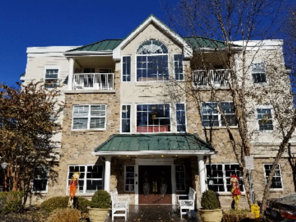 A multi-story residential building with balconies and large windows under a clear blue sky.