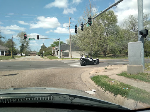 A motorcycle navigating an intersection with traffic lights on a cloudy day.