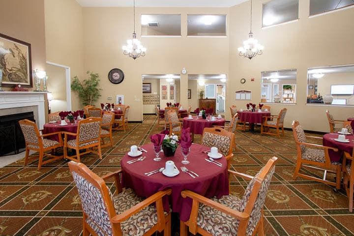 An elegant dining room with neatly set tables and comfortable chairs under warm lighting.