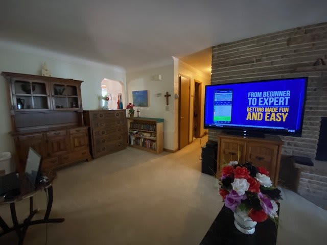 A cozy living room featuring a television, wooden furniture, and decorative flowers.