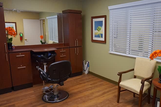A cozy salon interior featuring a barber chair, mirror, and wooden furniture.