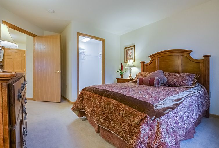 A cozy bedroom with a large bed, decorative pillows, and a wooden headboard.