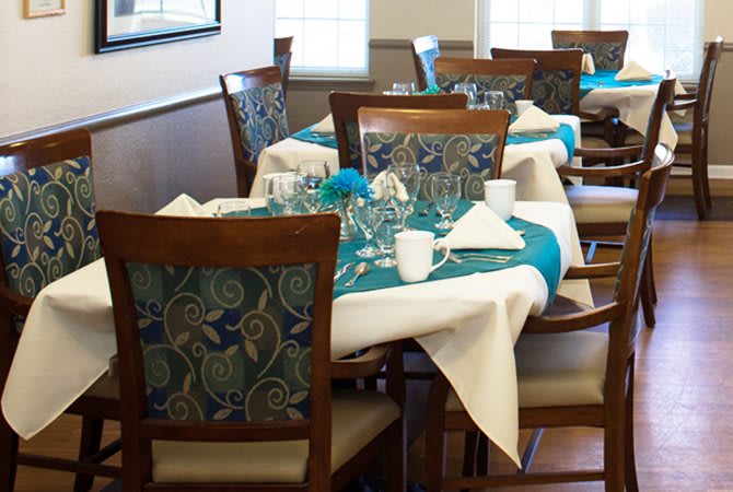A cozy dining area setup with elegantly arranged tables, adorned with patterned chairs and glassware.