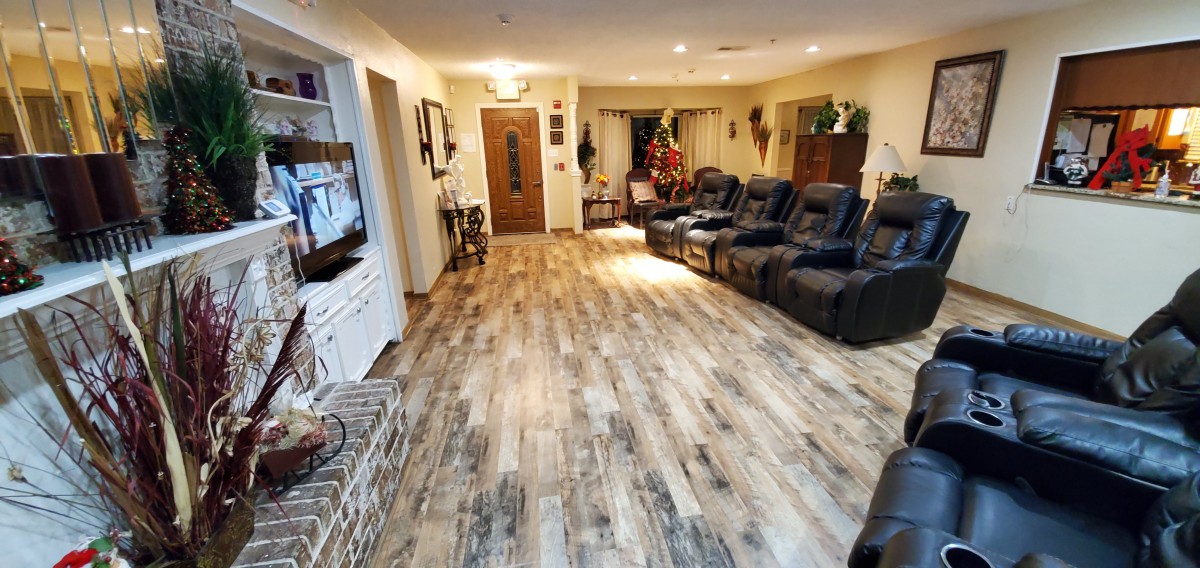 A cozy living room with hardwood floors, reclining chairs, and warm lighting.