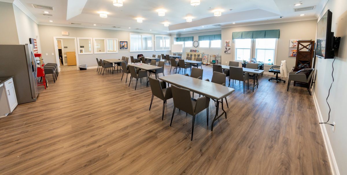 An empty conference room with arranged tables and chairs, illuminated by bright overhead lights.