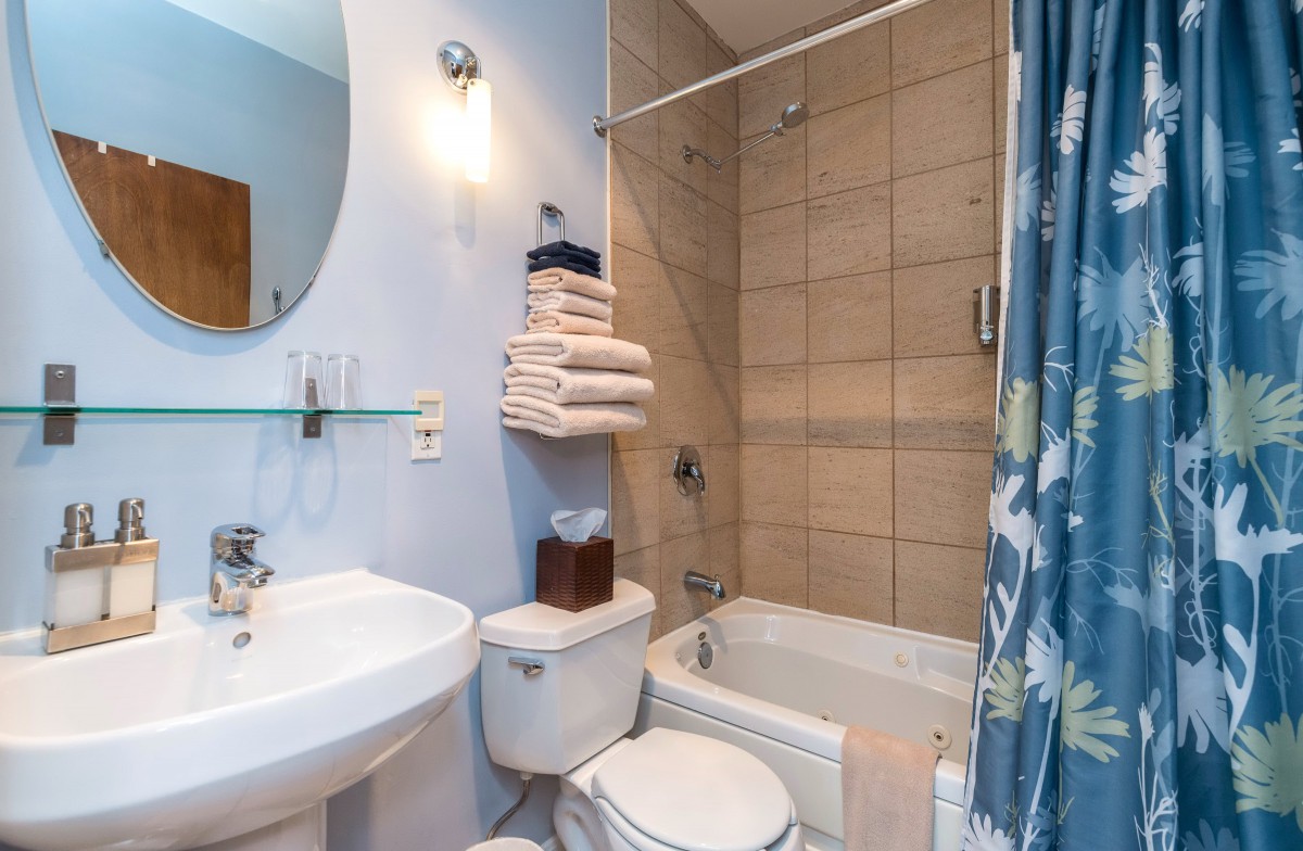 A clean and organized bathroom with a pedestal sink, toilet, and a tub shower combination.