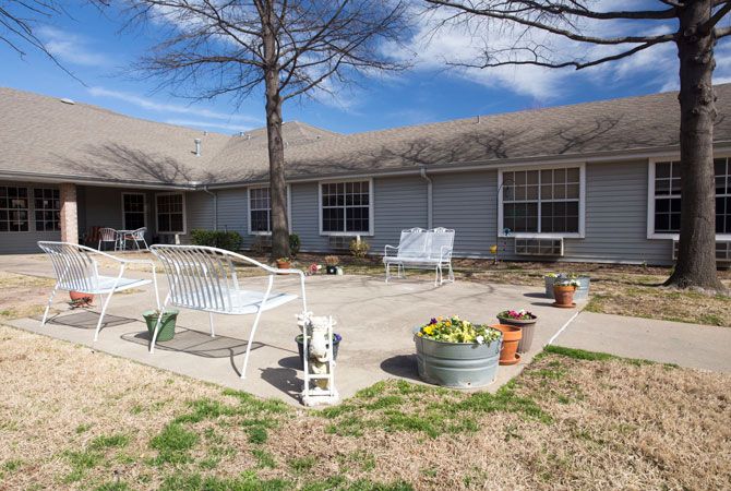 A backyard patio area with outdoor furniture and potted plants in front of a house.