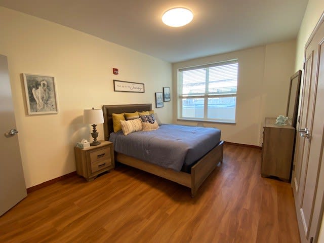 A cozy bedroom with a large bed, nightstands, and wooden flooring.